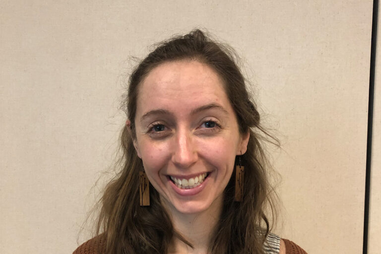 Woman with shoulder length brown hair and striped shirt smiling