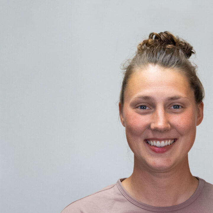 Claire-Tomashek-Blog-Post Headshot of woman with light brown shirt and messy bun