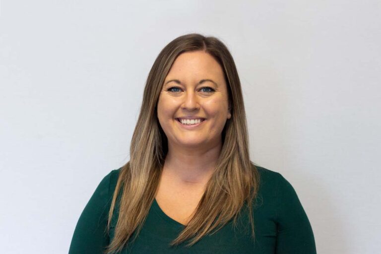 Headshot of woman with long blonde/brown hair and dark green shirt