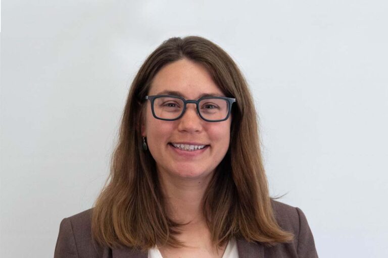 Headshot of woman with brown medium length hair and black glasses