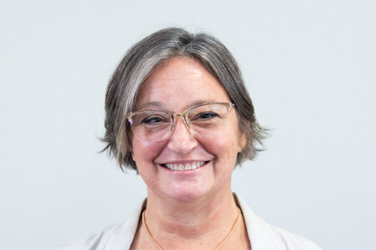 Headshot of woman smiling with glasses and short hair