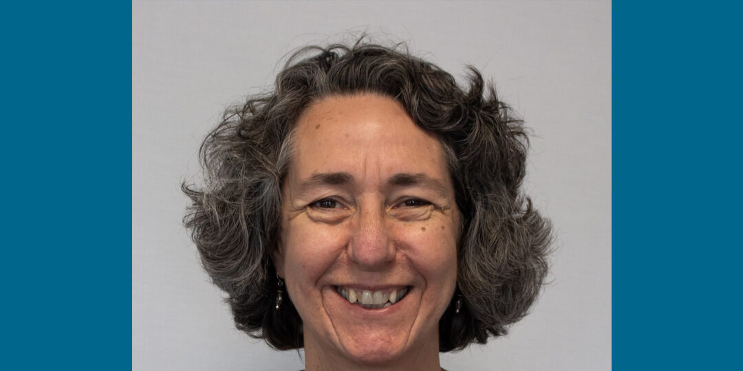 Headshot of woman with dark gray ear-length hair and big smile