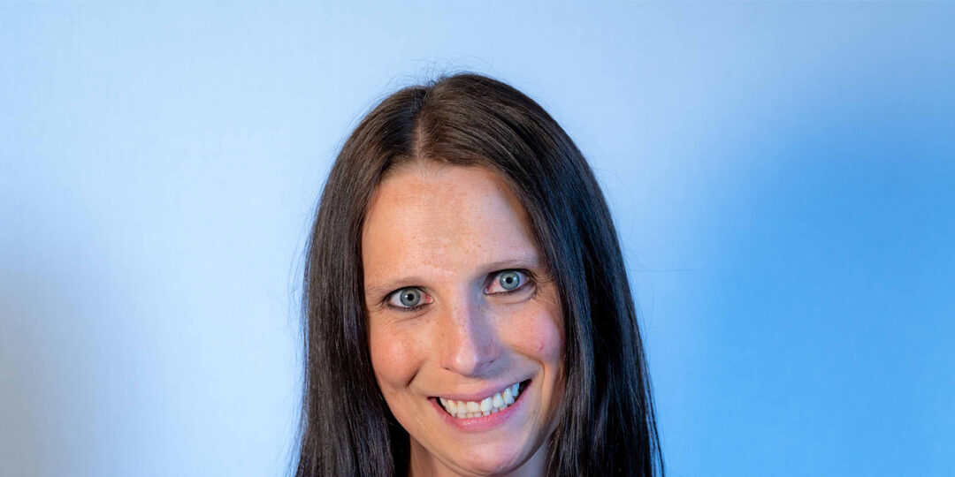 Headshot of woman with light blue eyes and dark long hair