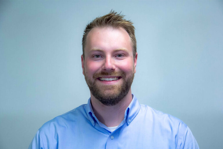 Headshot of man with dirty blonde hair and bird in light blue button up