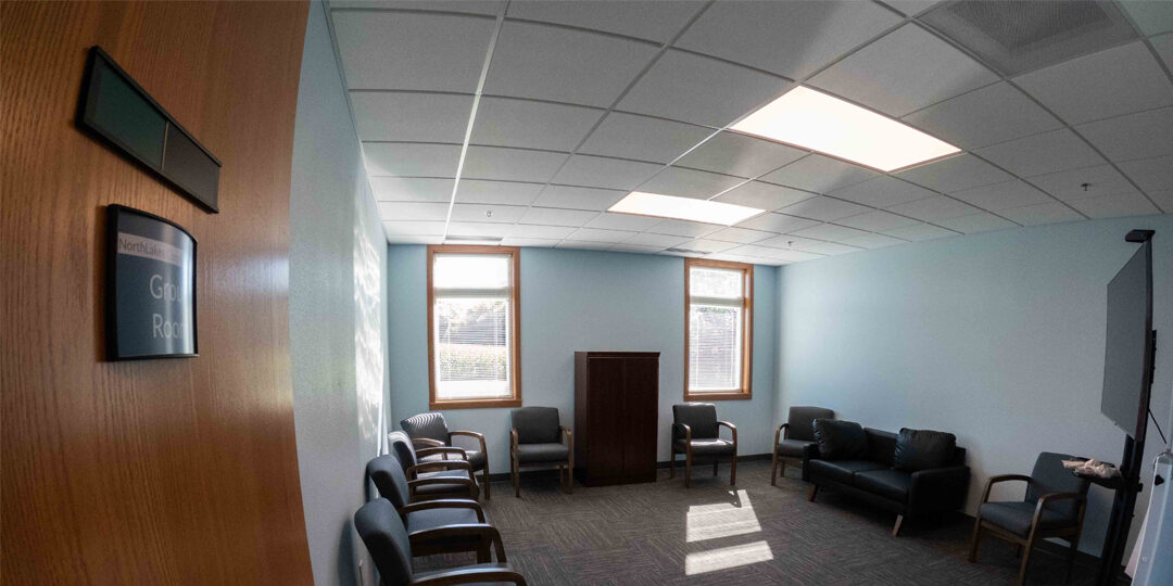 Turtle-Lake-Clinic-Group-Room Carpeted office room with chairs along the walls