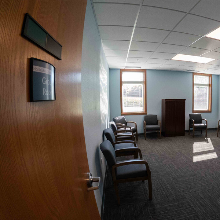 Turtle-Lake-Clinic-Group-Room Carpeted office room with chairs along the walls