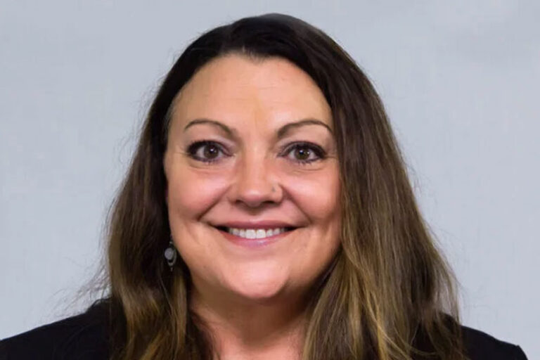 Headshot of woman with long brown hair and brown eyes, smiling