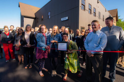Large group of staff members standing in front of Hayward clinic and cutting reb ribbon