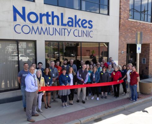 Staff members standing outside of NorthLakes Community Clinic in front of large red ribbon