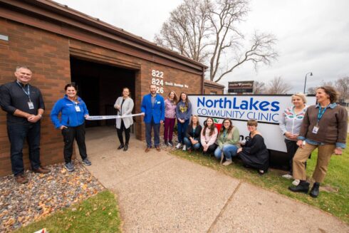 Staff members outside of building cutting a white ribbon