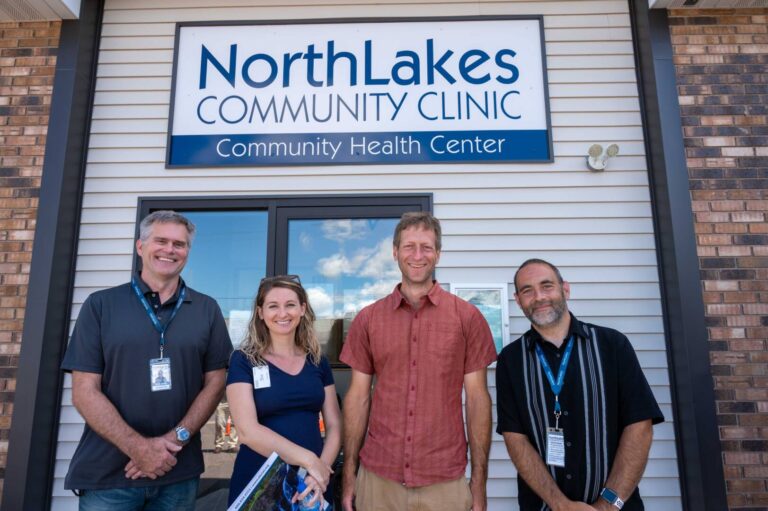 4 staff members smiling in front of clinic sign