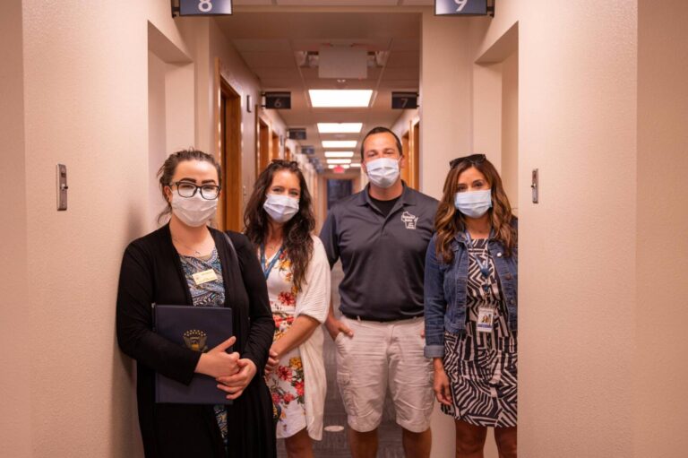 4 staff members wearing face masks in clinic hallway