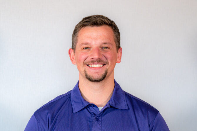 Headshot of man with dark blue shirt and short brown hair