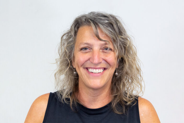Woman with shoulder length curly light hair and black tank top