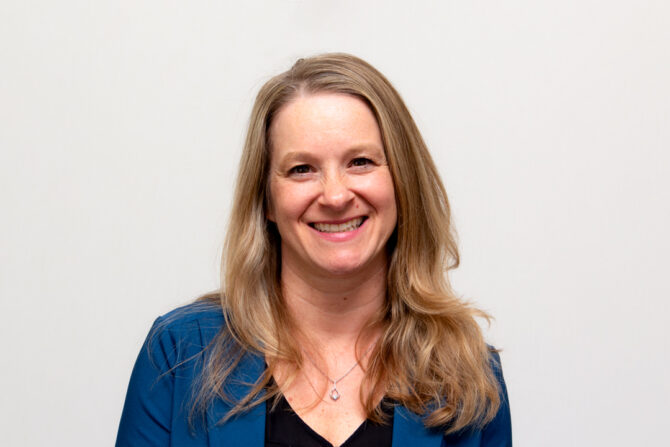 Headshot of woman smiling with long blonde hair and blue blazer