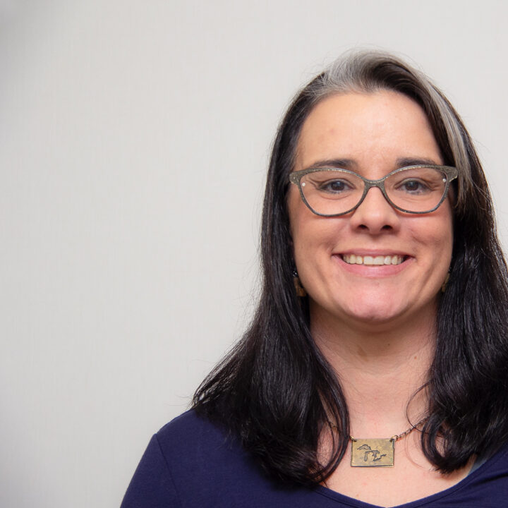 Holly M Spletzer Provider Photo Featured Image Headshot of woman smiling with shoulder length black hair and blond highlight, wearing glasses