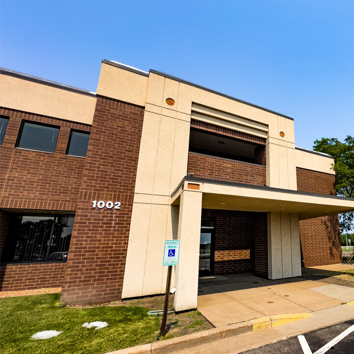 Eau-Claire-Clairemont-Avenue-Featured-Image Outside of large brick building with green grass and blue sky. Tall NorthLakes sign in front