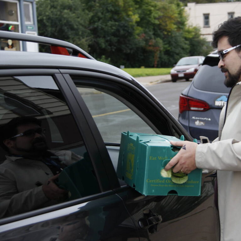 NorthLakes-Farm to Table man handing green food bin through car window