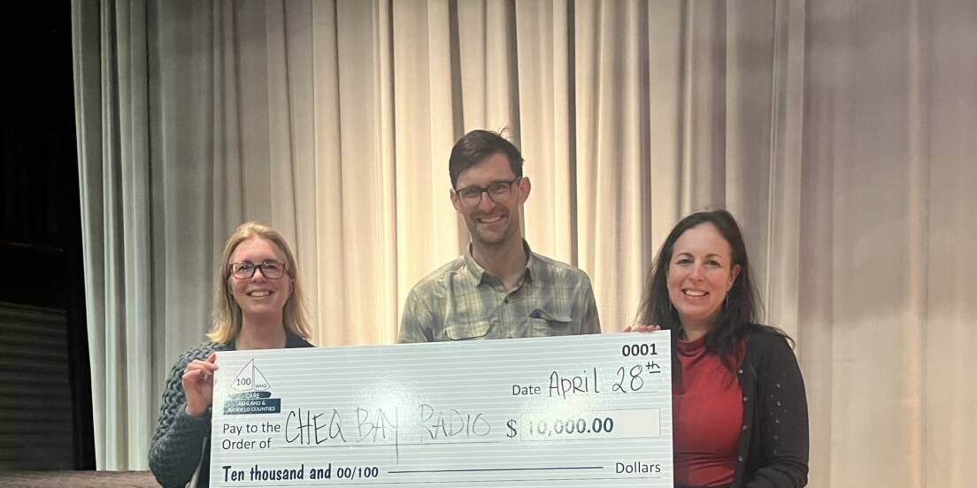 three people holding a large check as a donation