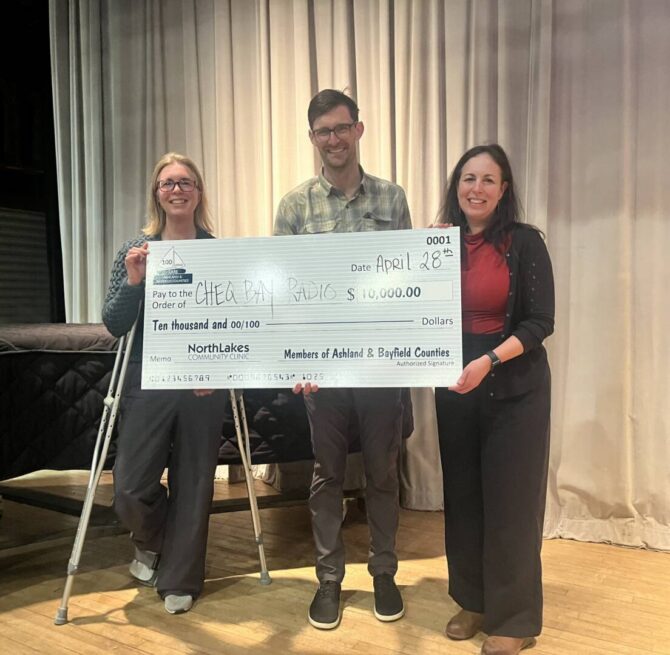 three people holding a large check as a donation