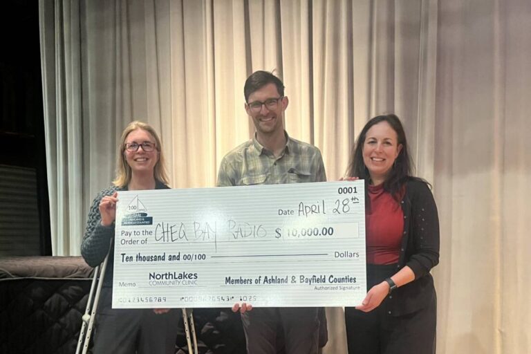 three people holding a large check as a donation