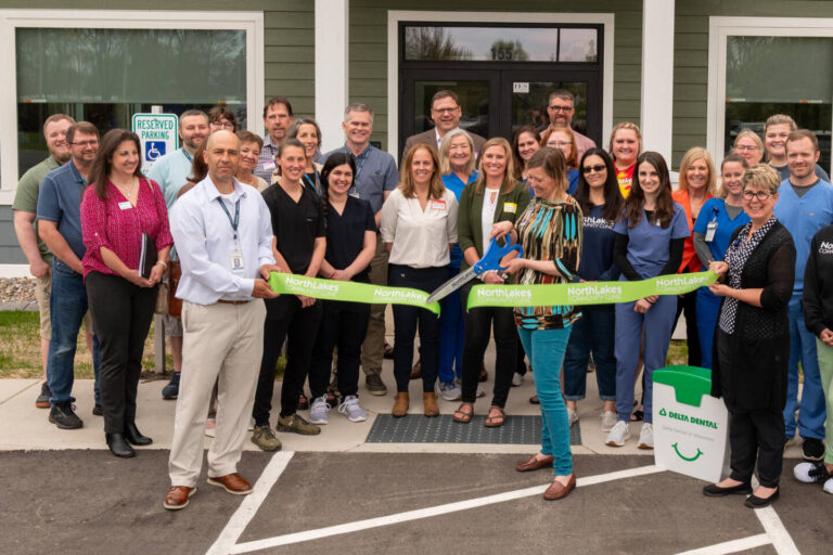 Large group of staff members around a green ribbon