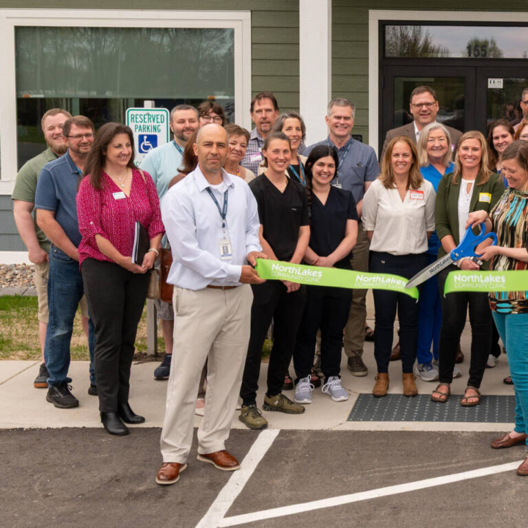 Oconto Ribbon Cutting Large group of staff members around a green ribbon