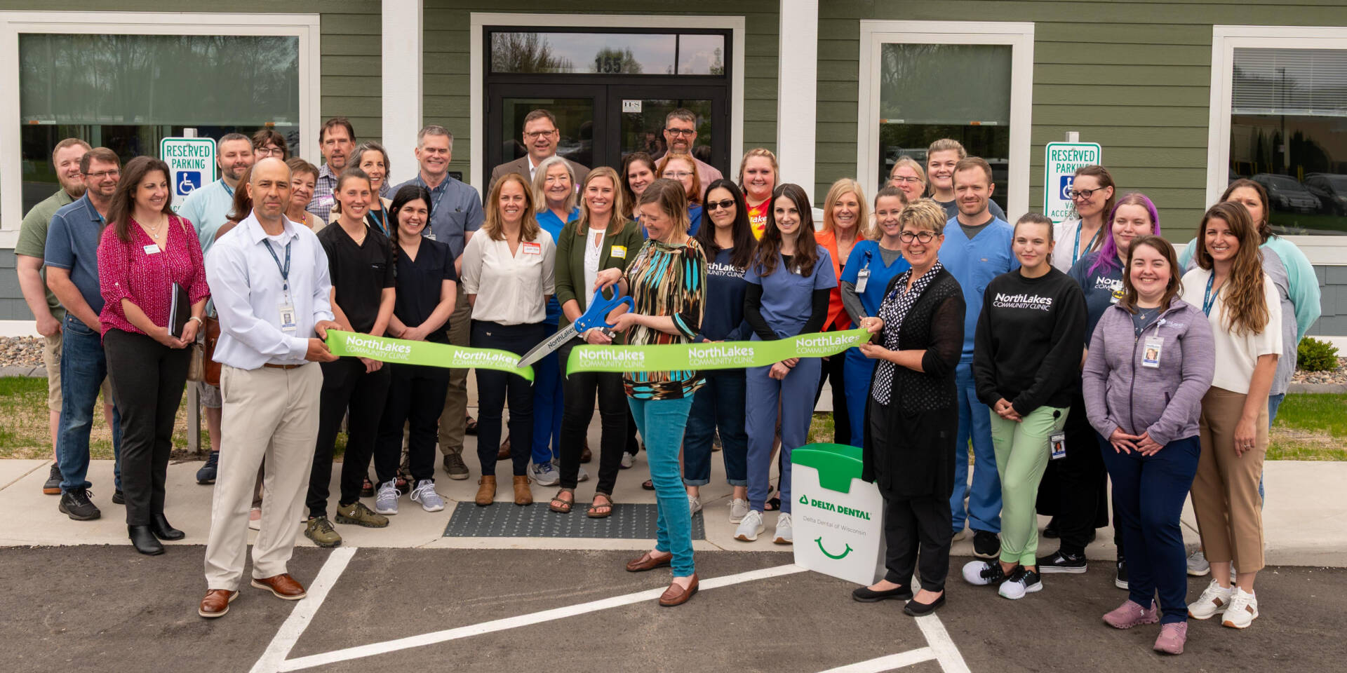 Large group of staff members around a green ribbon