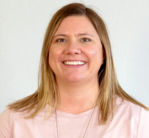 Woman with blonde shoulder-length hair, brown eyes, and pink top