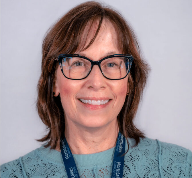 Woman with brown hair, black glasses, and blue blouse