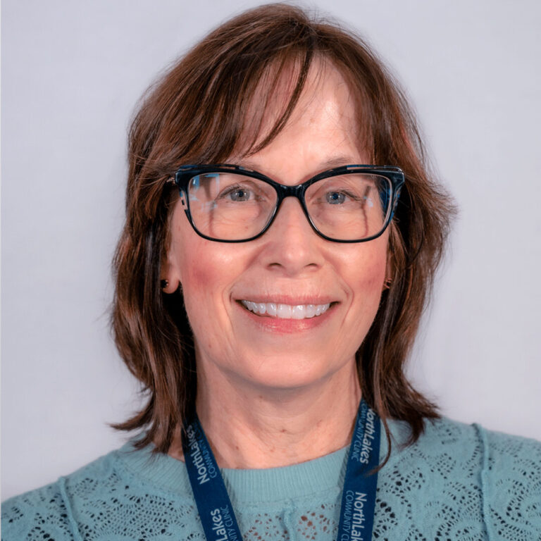 Woman with brown hair, black glasses, and blue blouse
