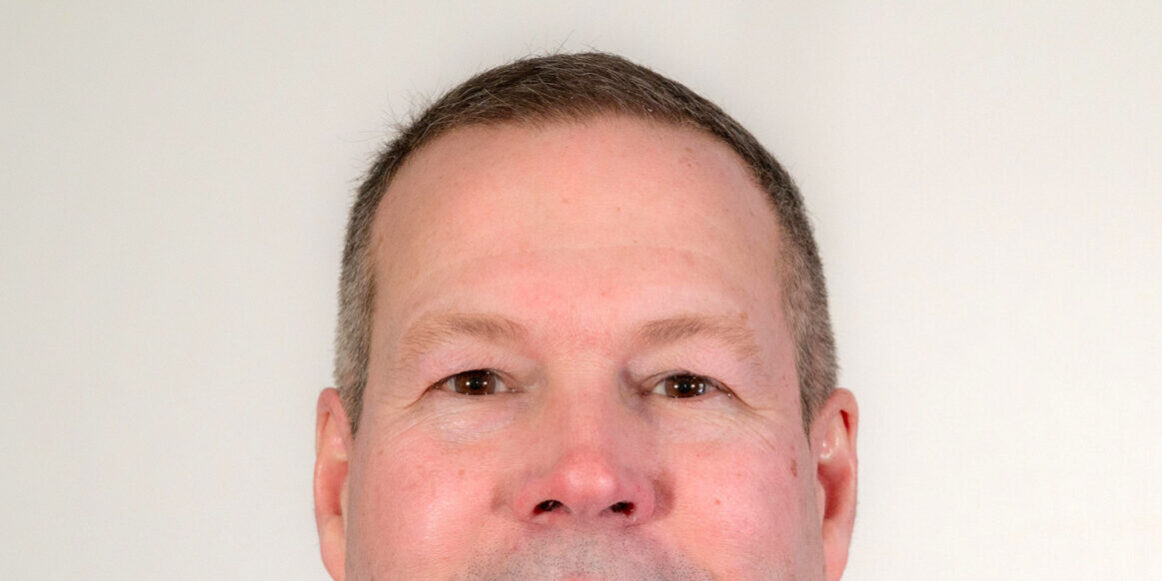 Man with short dark hair and sweater with collar