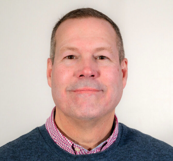 Man with short dark hair and sweater with collar