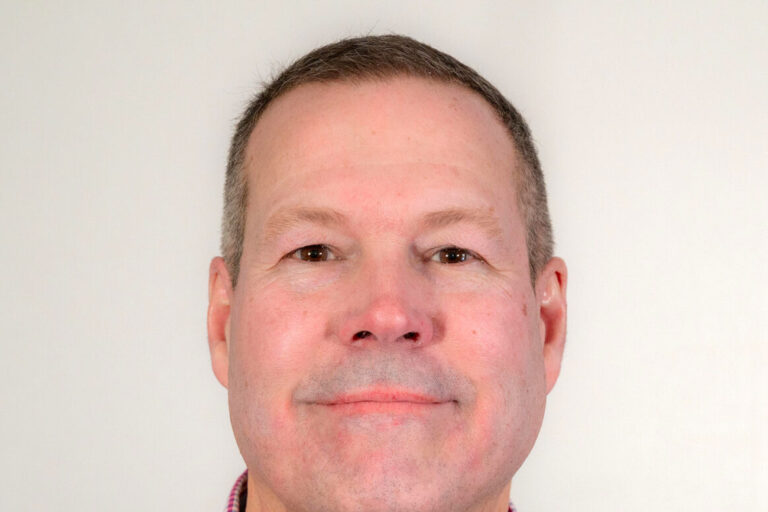 Man with short dark hair and sweater with collar