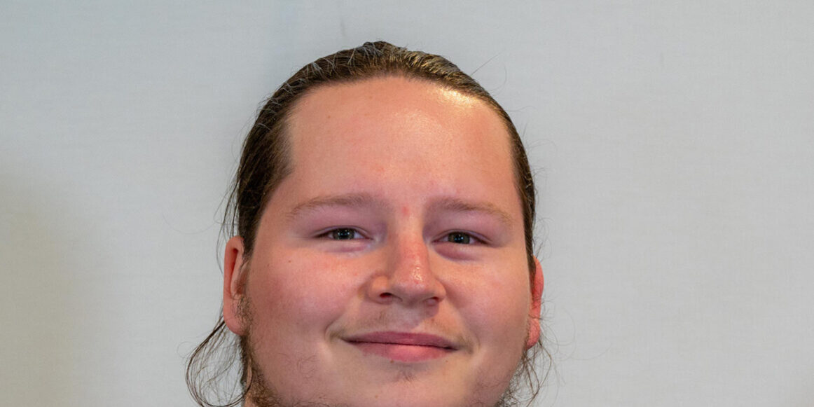 Man with dark hair and beard in dark blue scrub top
