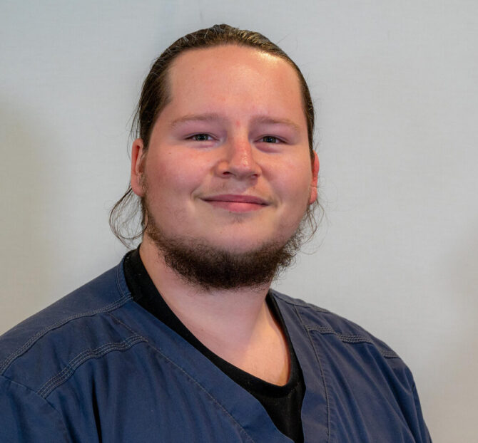 Man with dark hair and beard in dark blue scrub top