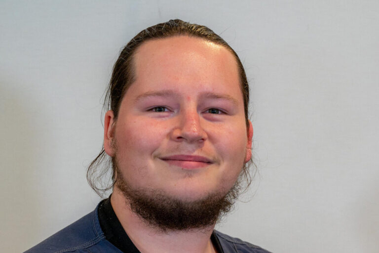 Man with dark hair and beard in dark blue scrub top