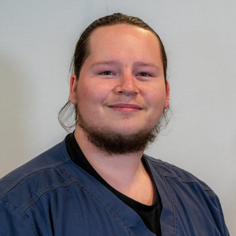 Man with dark hair and beard in dark blue scrub top