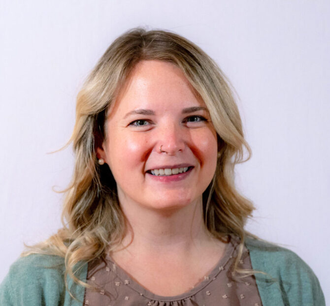 Woman with curled blonde hair smiling in a headshot