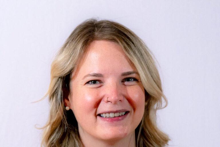 Woman with curled blonde hair smiling in a headshot