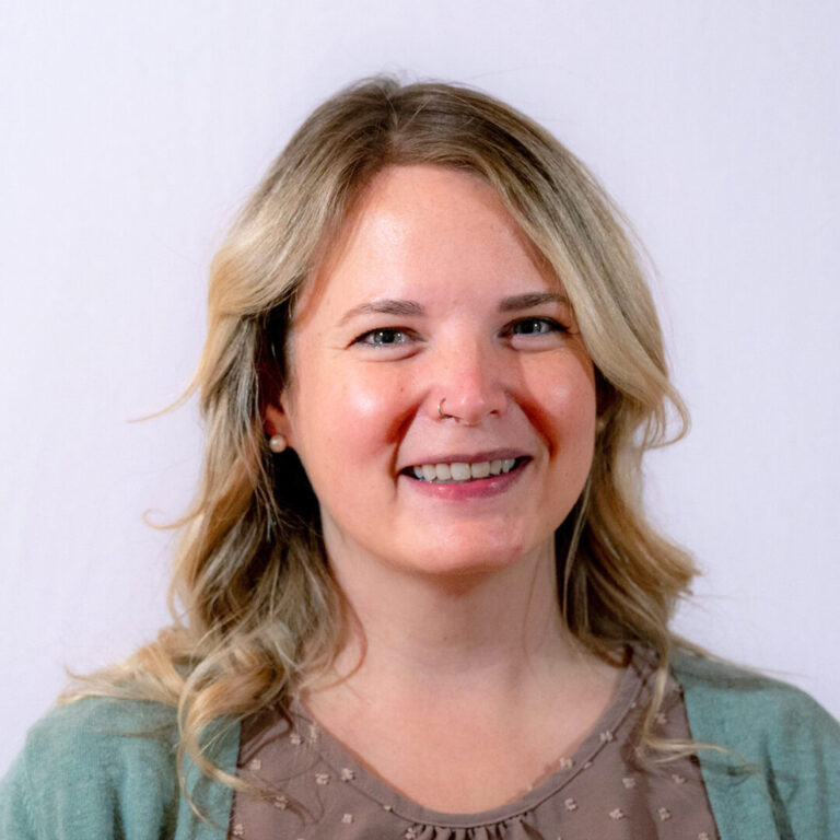 Woman with curled blonde hair smiling in a headshot