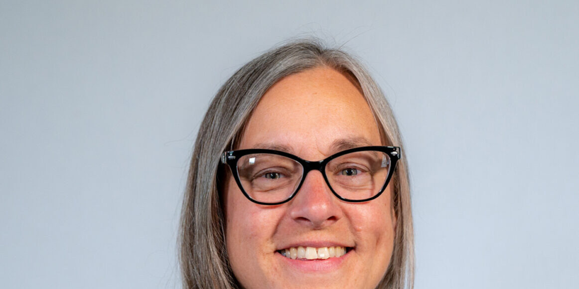 headshot woman with glasses and blue shirt