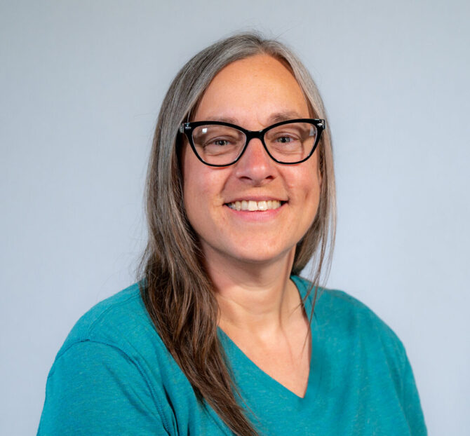 Katie Mazur Web headshot woman with glasses and blue shirt