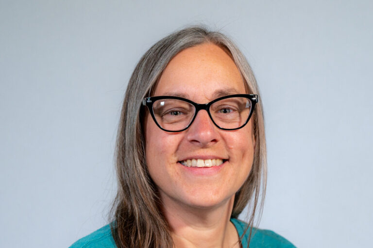 headshot woman with glasses and blue shirt