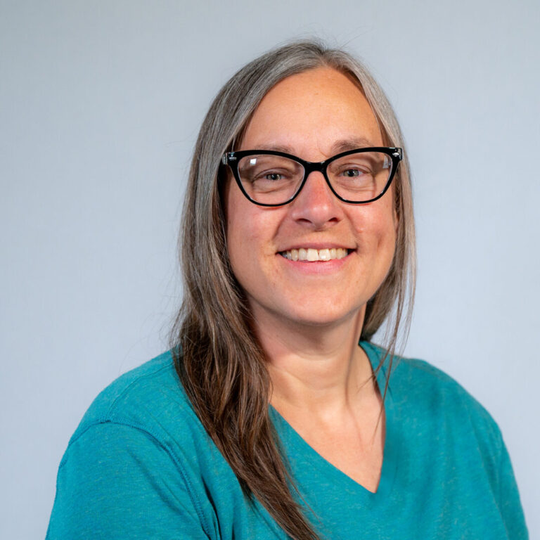 Katie Mazur Web headshot woman with glasses and blue shirt