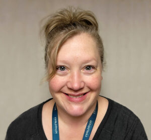Headshot of woman with black top and blonde hair in a ponytail