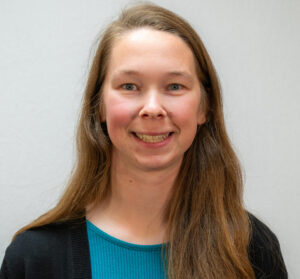 Headshot of woman with long hair and blue top with black jacket