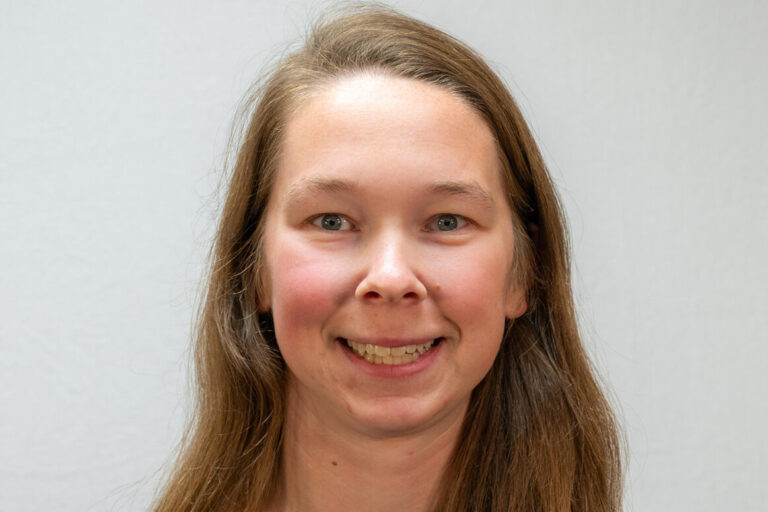 Headshot of woman with long hair and blue top with black jacket