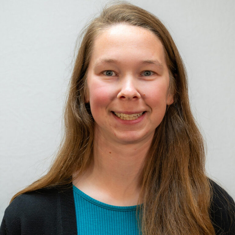 Headshot of woman with long hair and blue top with black jacket