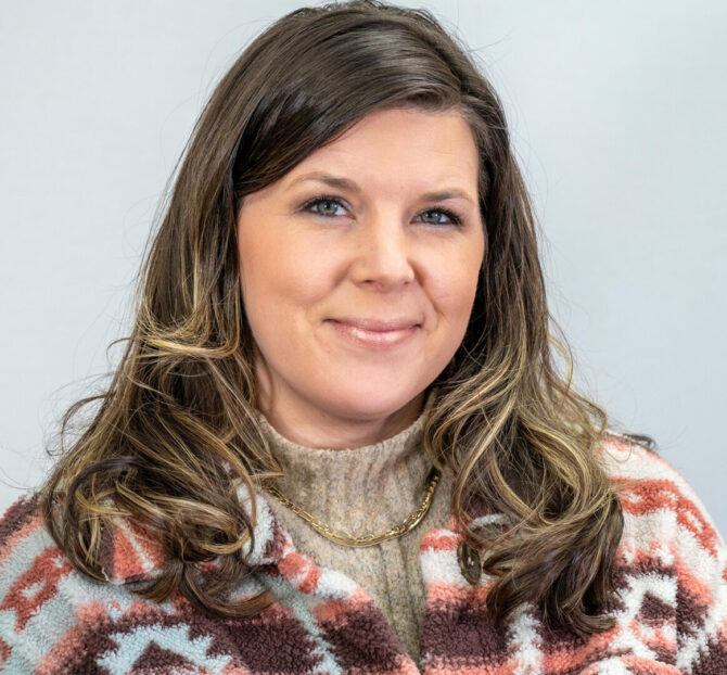Headshot of woman smiling with long brown hair and turtleneck